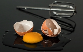 Cracked egg and a beater on a counter
