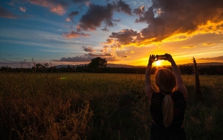 Woman takes photo of the sunset with her smartphone